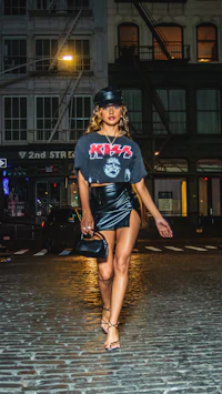 a woman in a leather skirt walking down a cobblestone street at night